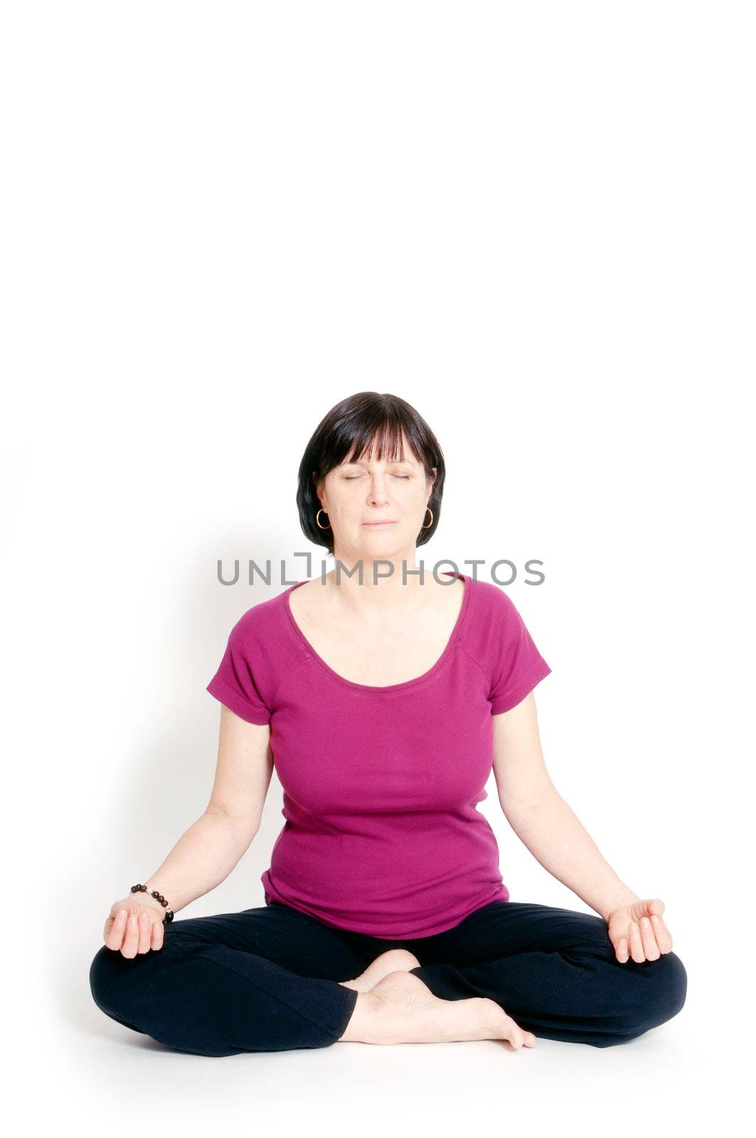 Aged woman sitting in lotus seat practicing yoga.
