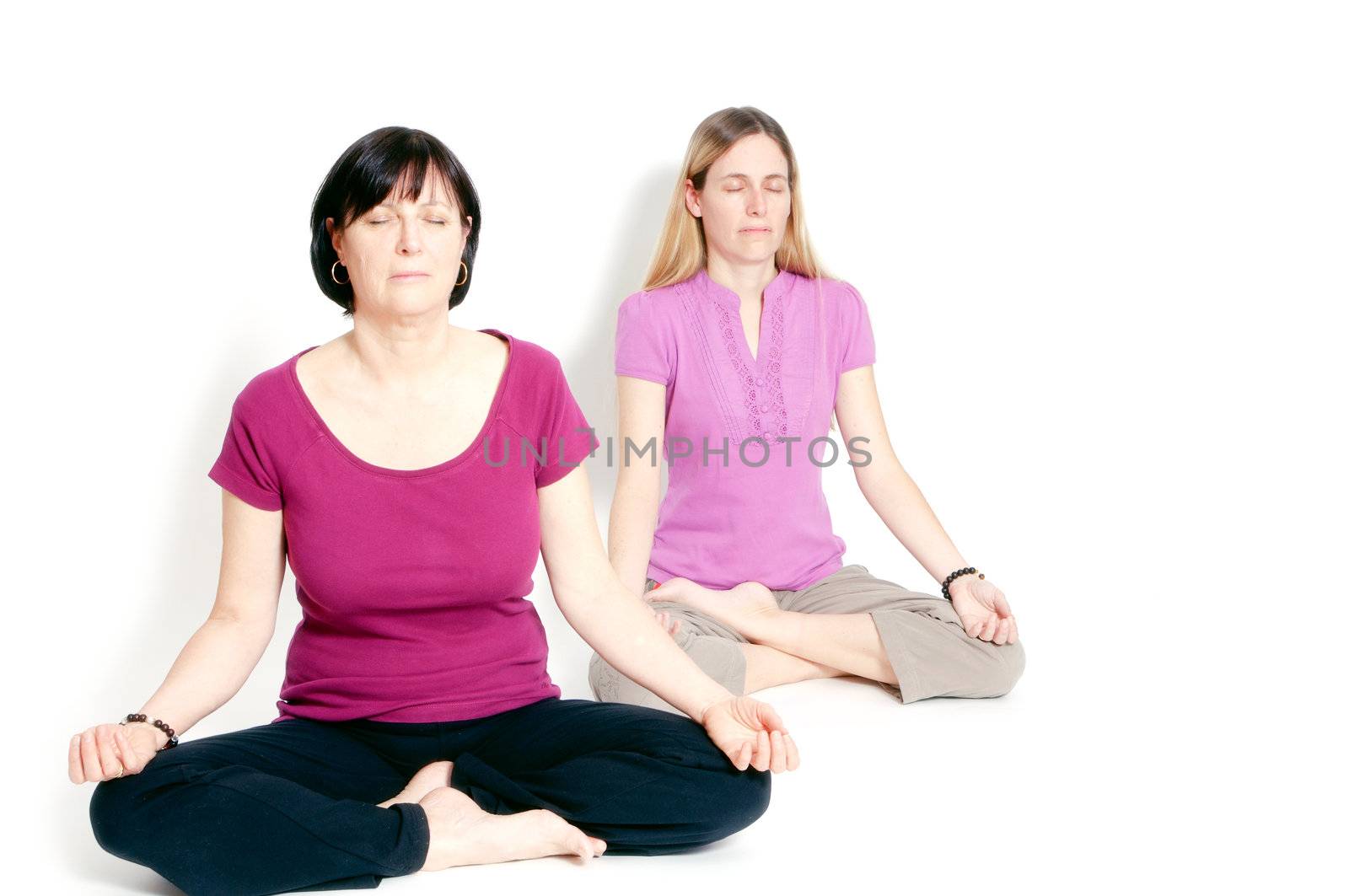 Young and old woman sitting in lotus seat practicing yoga together