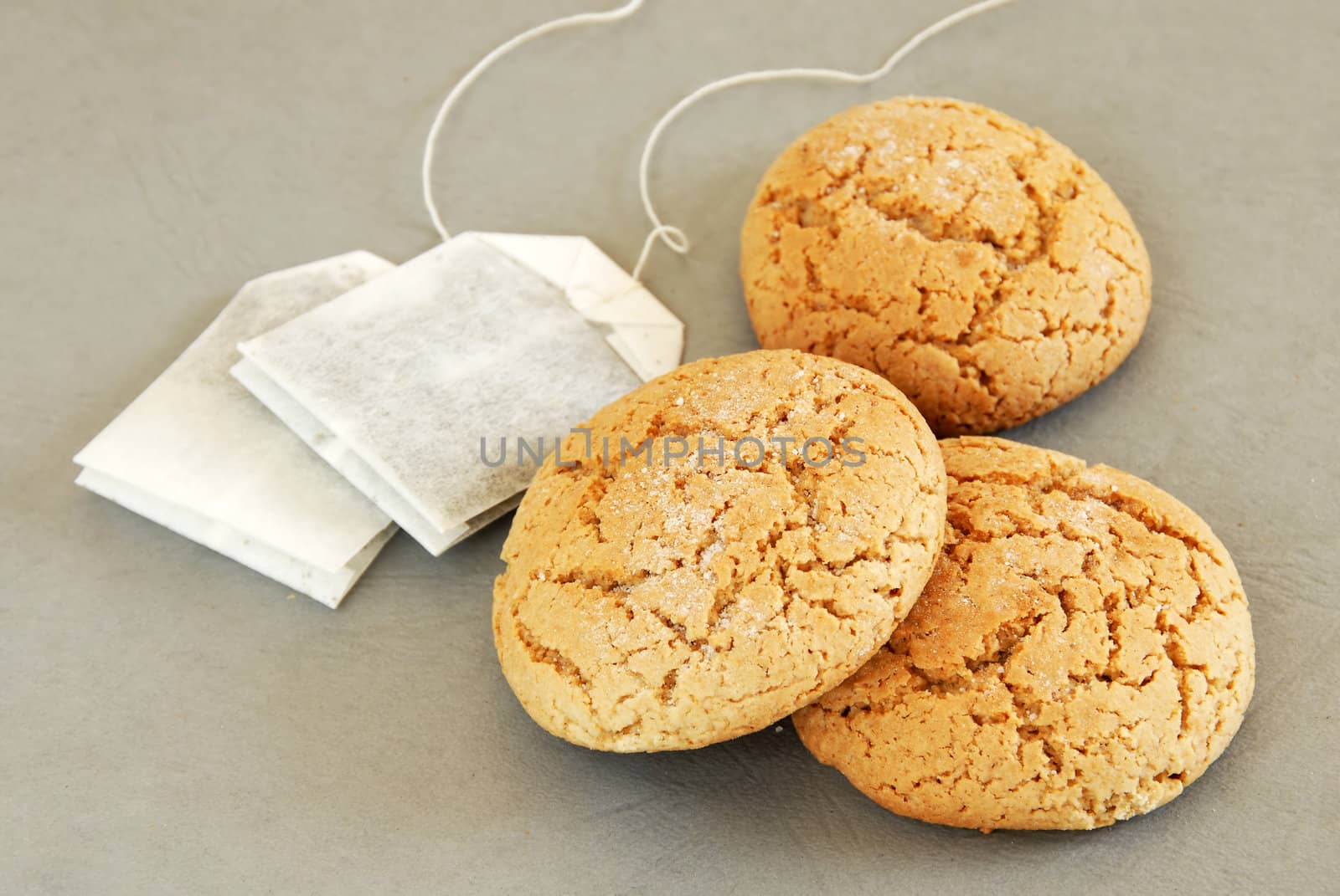 three fresh appetizing oatmeal cookies with tee bags over gray background