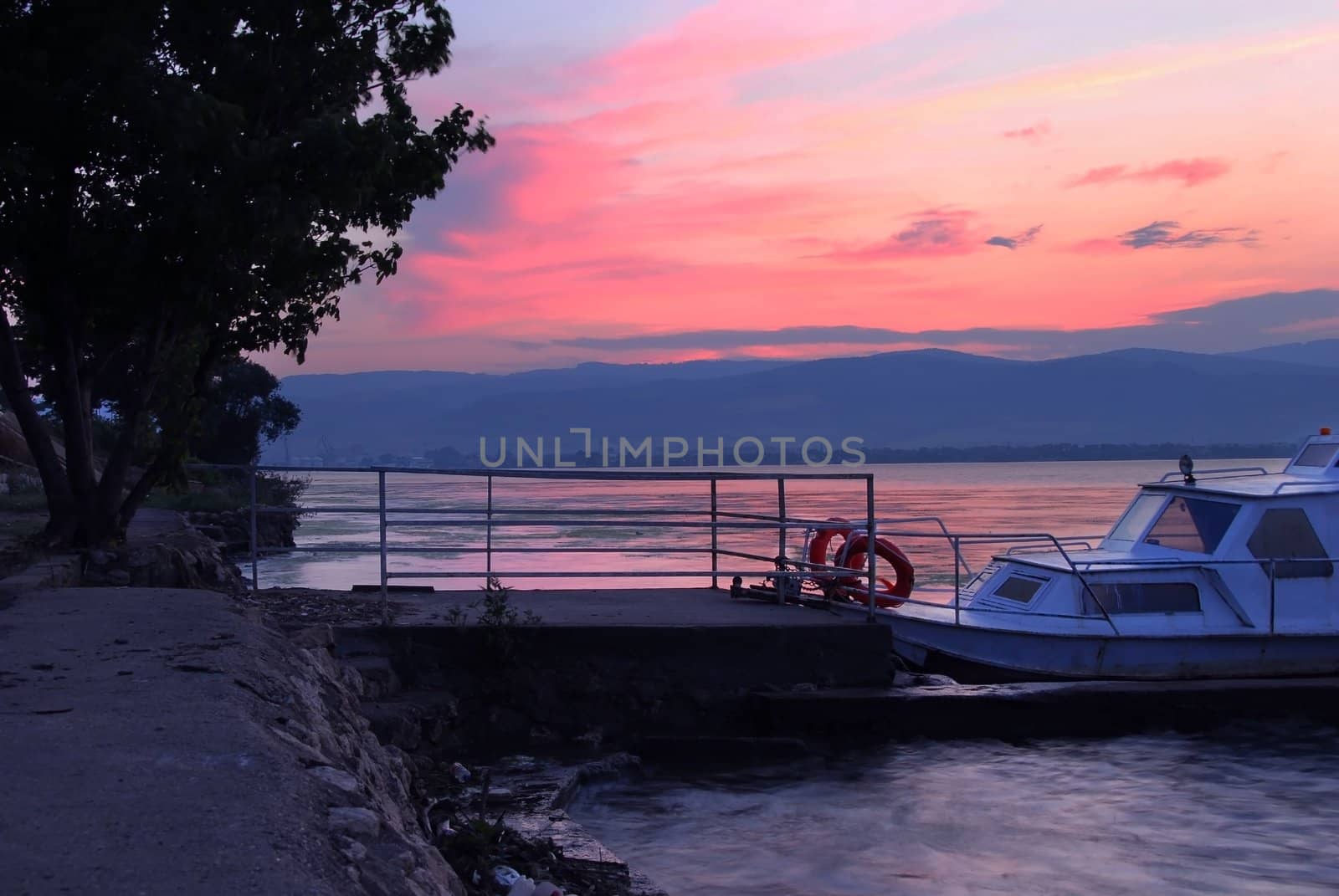 beautiful sunrise over Danube in Serbia, boat by riverbank