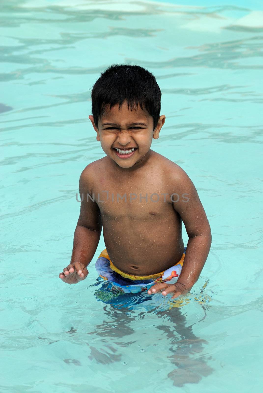 An handsome Indian kid ready to swim by the pool