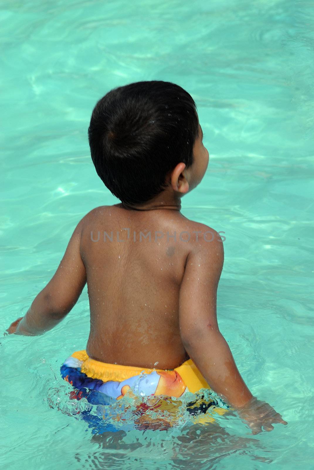 An handsome Indian kid ready to swim by the pool