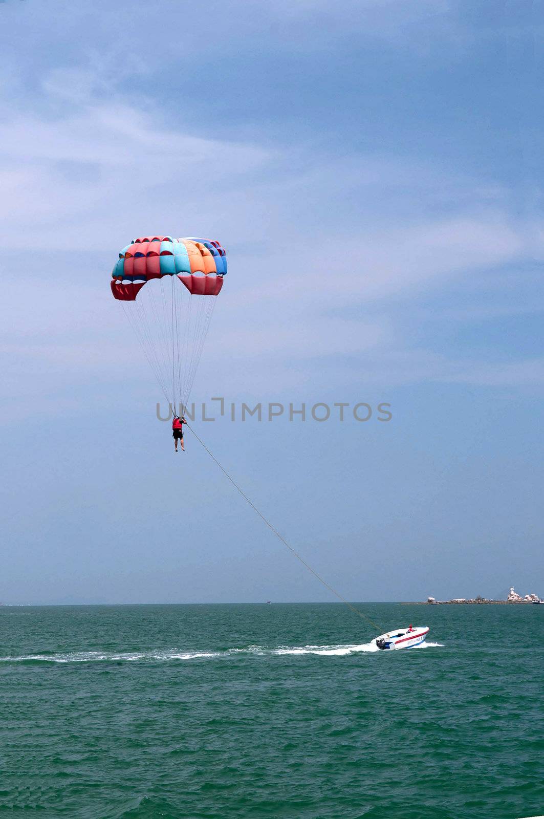 One man is parasailing over the clean sea.