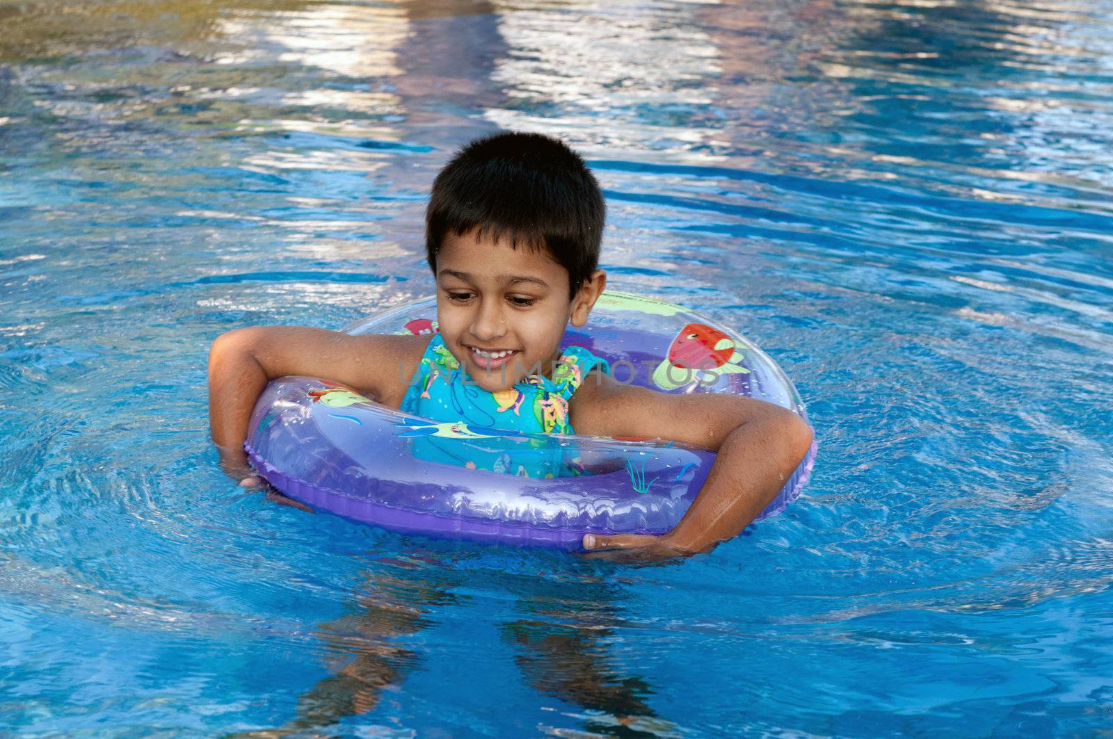 an handsome indian boy swimming happily in the pool