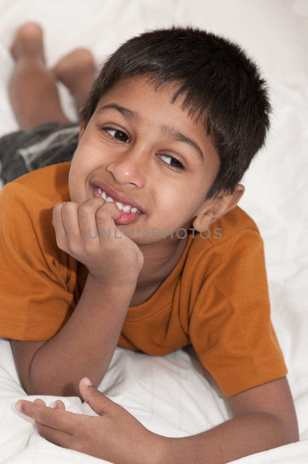 Handsome Indian kid lying happily on the bed