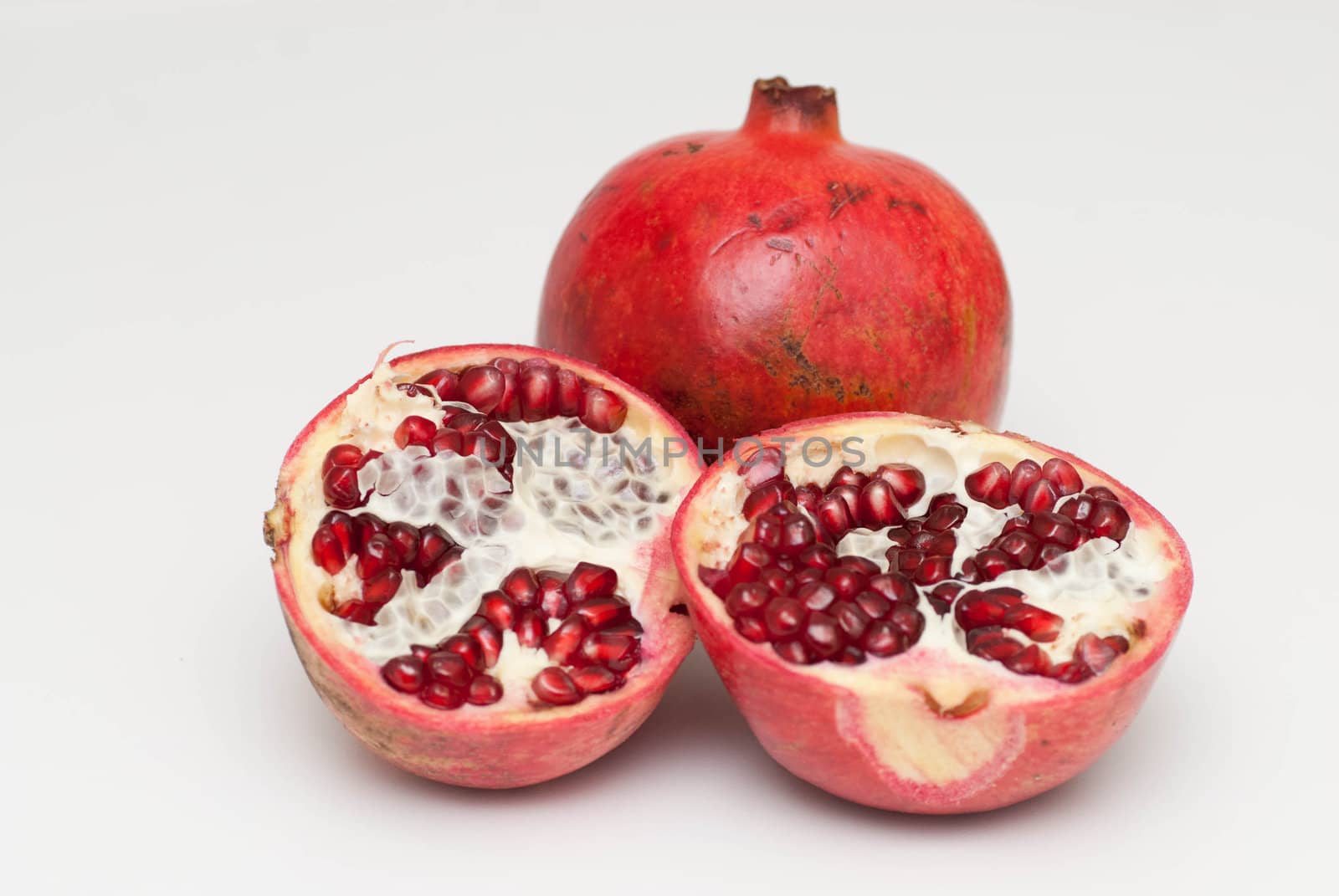 fresh cut pomegranate on a white background by pazham