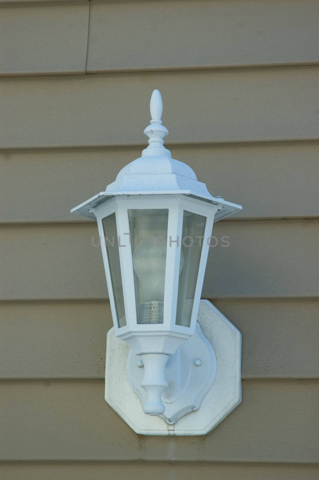 A white porch light against a brown vinal siding