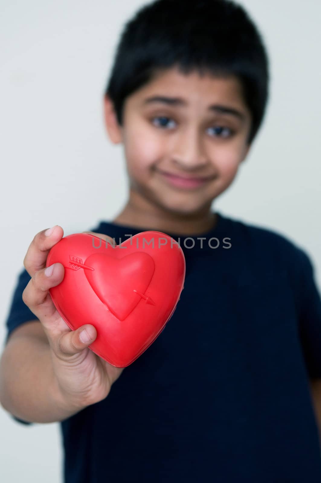 an handsome Indian kid holding out a red heart by pazham
