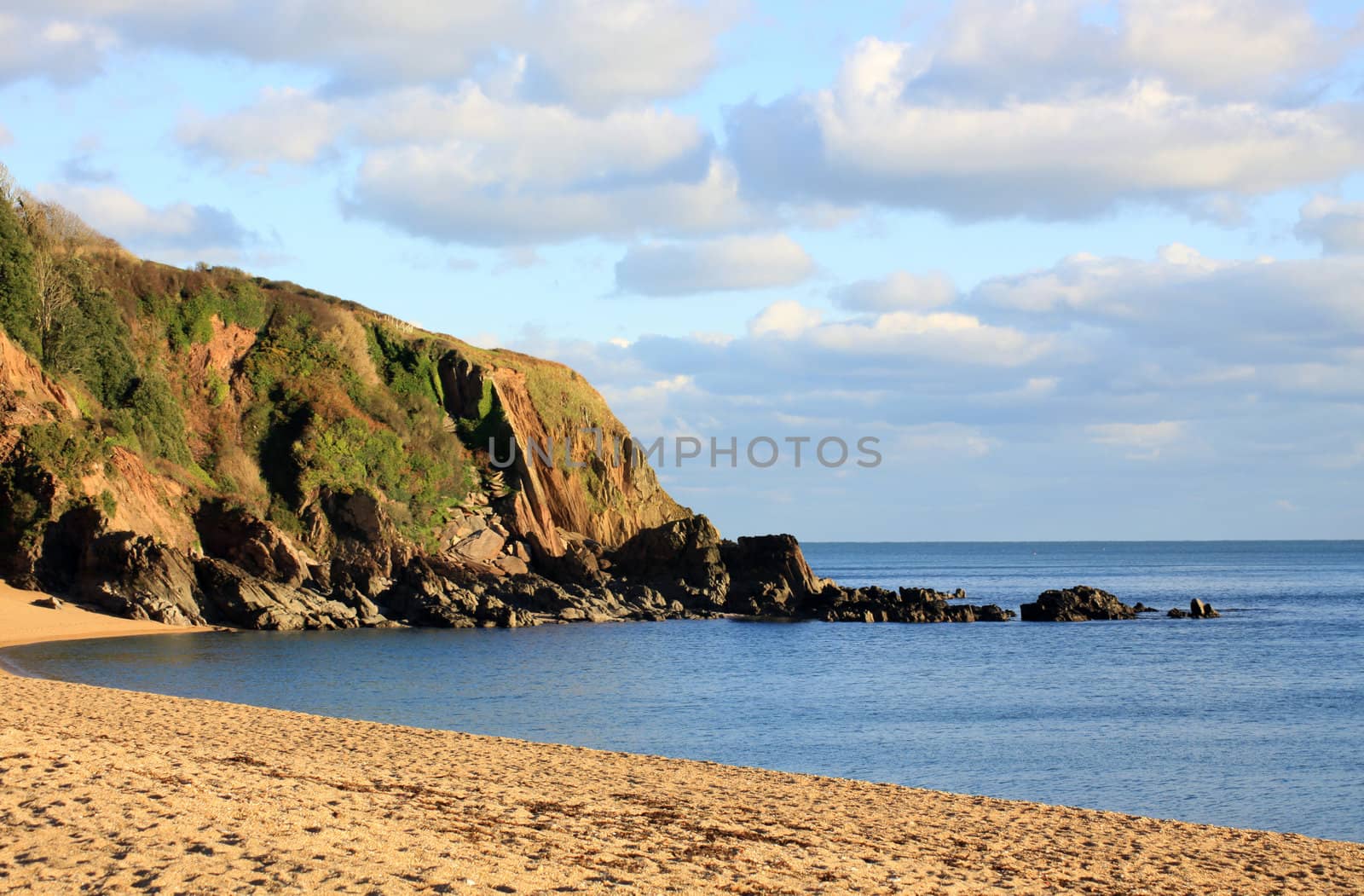 A winter beach scene. Late afternoon sunset over the cove at Blackpool Sands beach, Devon.