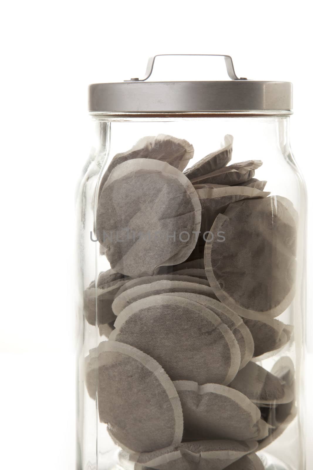 Coffie pads in jar on plain background.