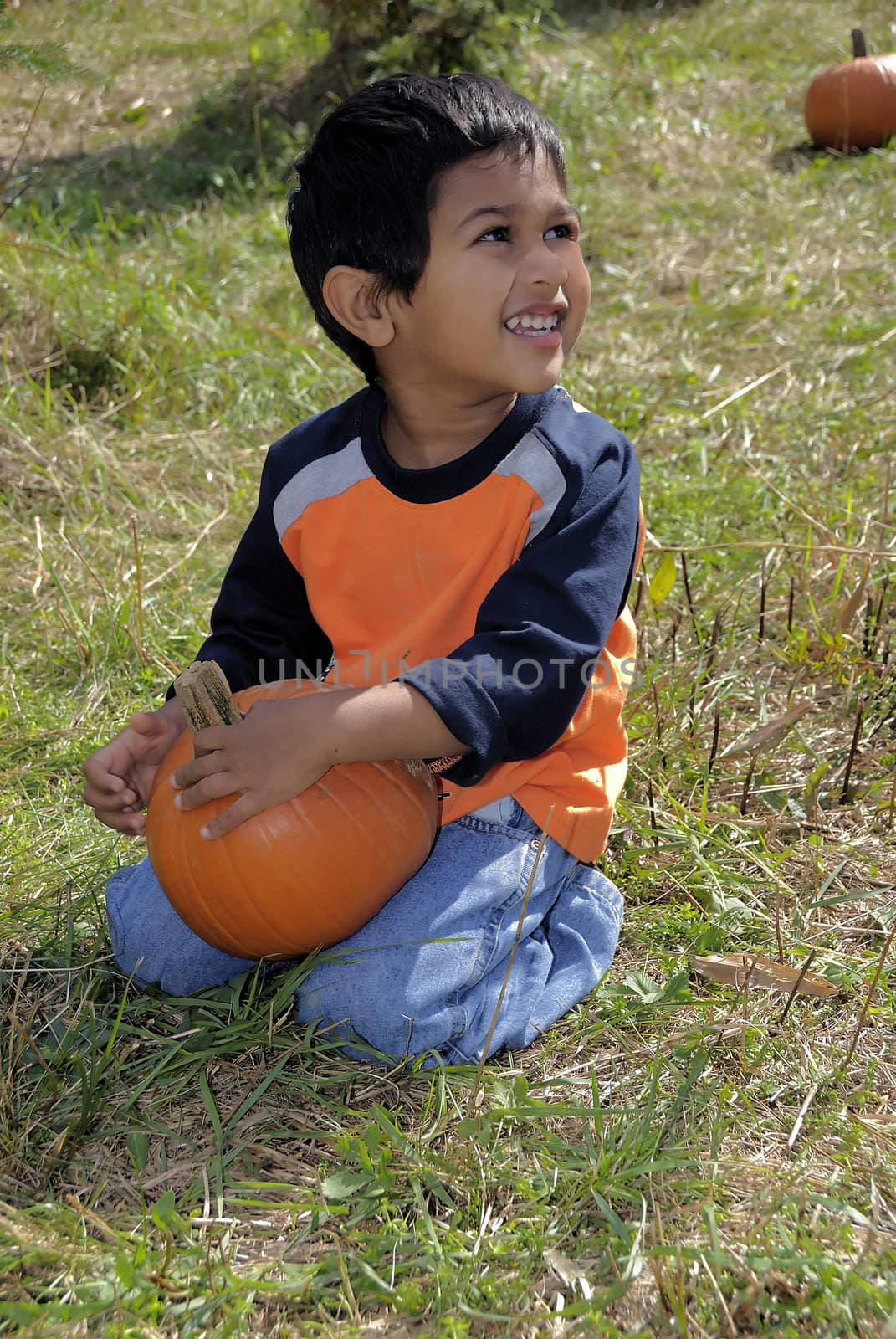 Handsome and smiling kid sitting with a pumpkin