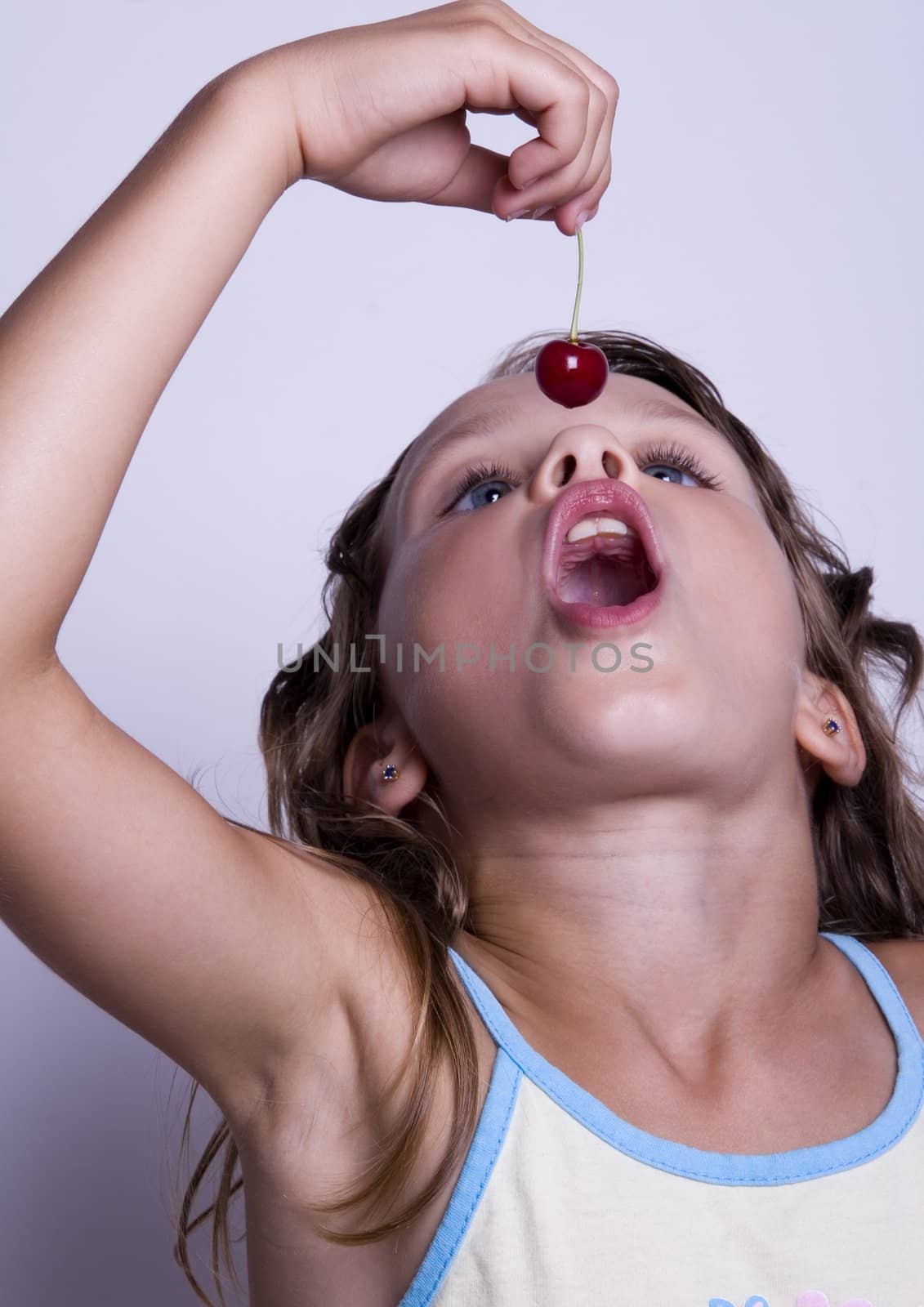 A sweet young girl eating fresh fruit. The child is on a white background