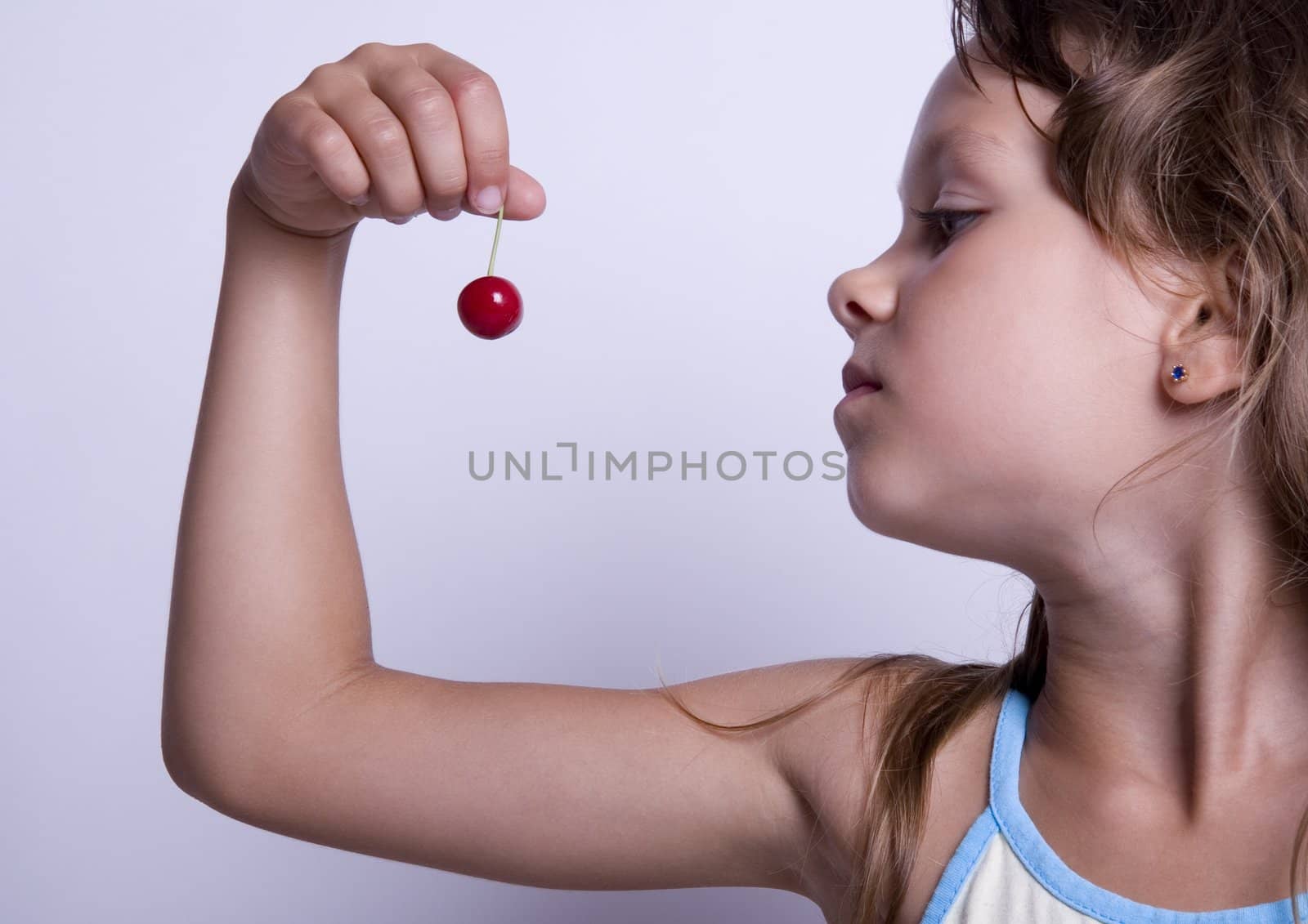 A sweet young girl eating fresh fruit. The child is on a white background