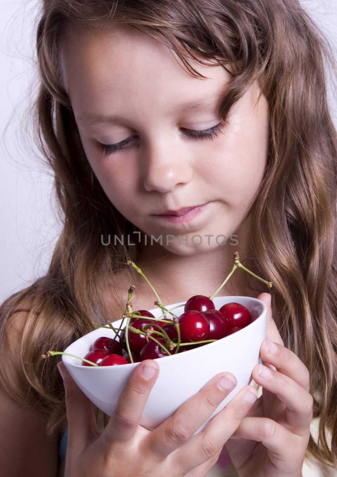 A sweet young girl eating fresh fruit. The child is on a white background