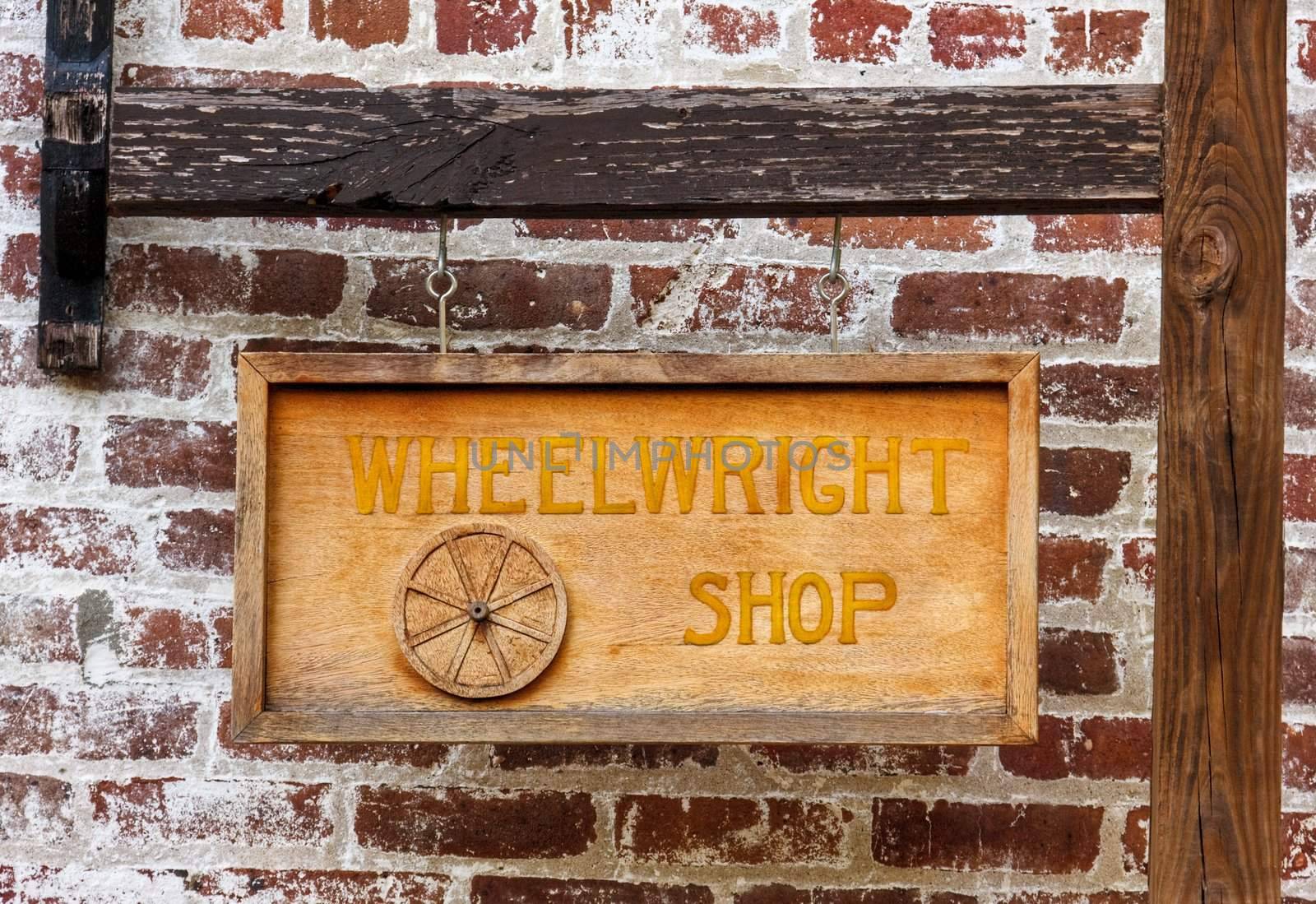 A wheelwright shop sign hanging in front of a brick wall