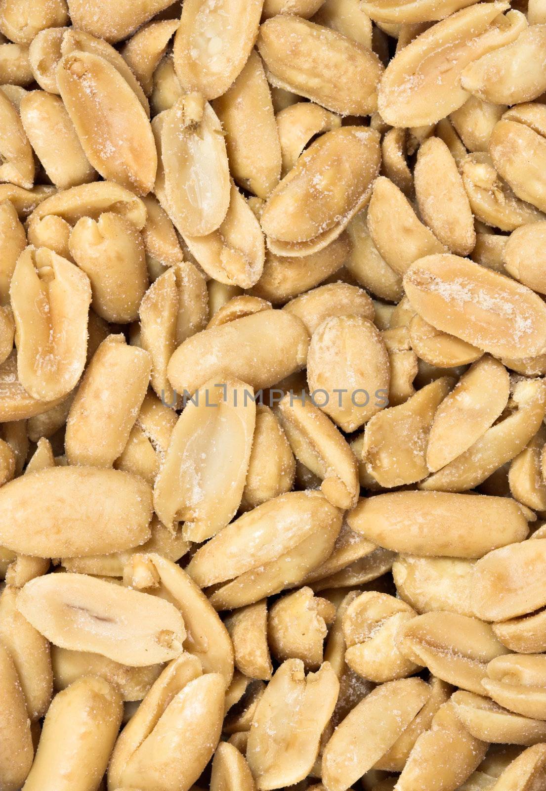 Detailed closeup of salted peanuts. The nuts fill the entire frame in portrait format.