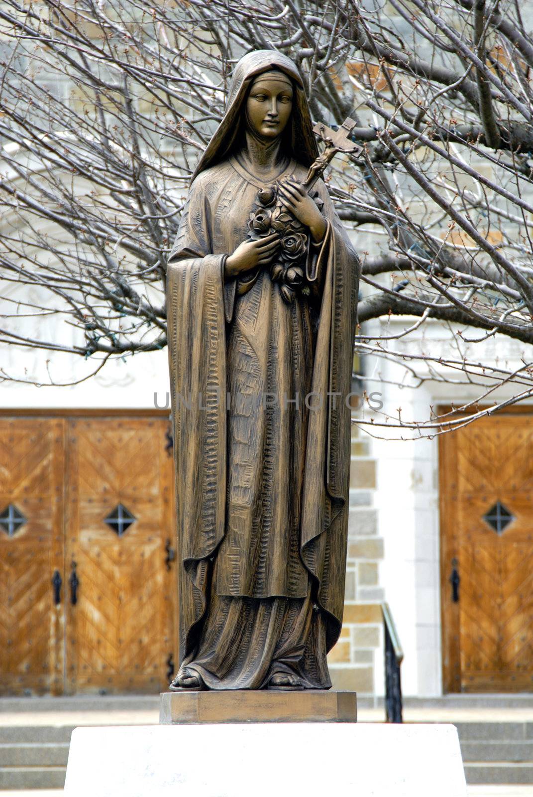 A metalic statue of Virgin mary in front of a catholic church