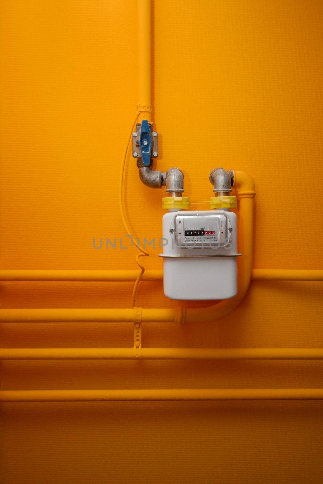 Pipes and gas meter on orange wall