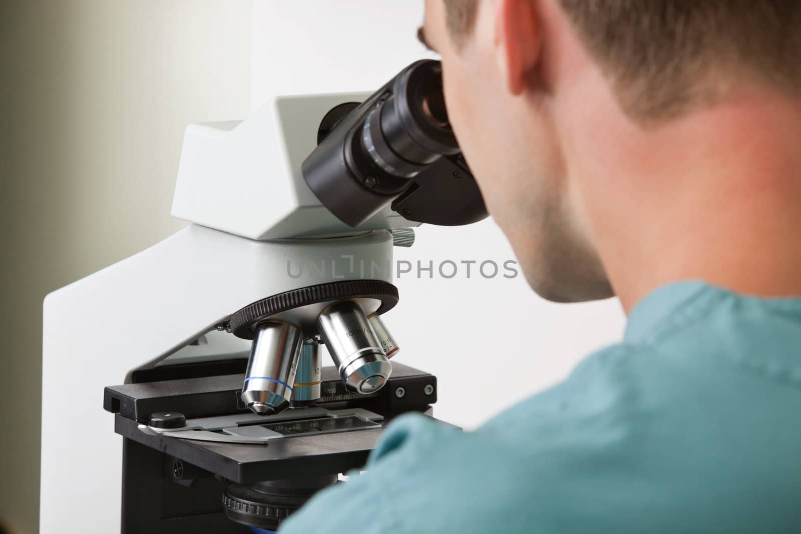 Closeup of young male doctor viewing through microscope