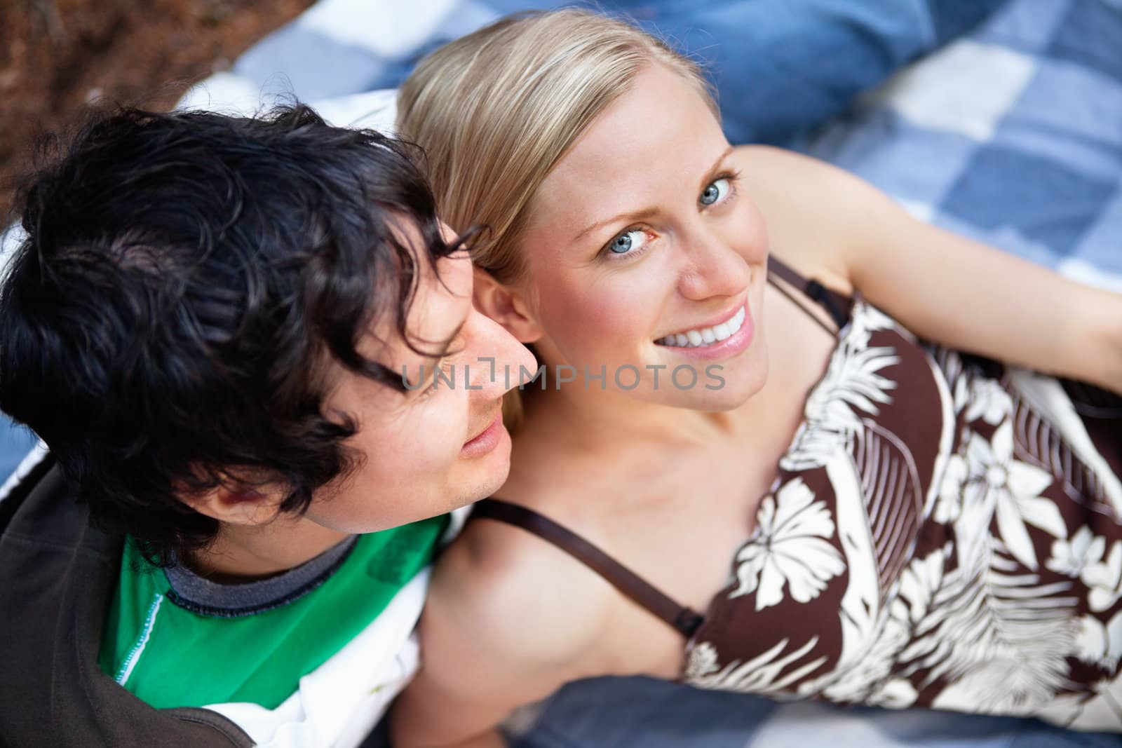 Young couple relaxing on picnic blanket by leaf