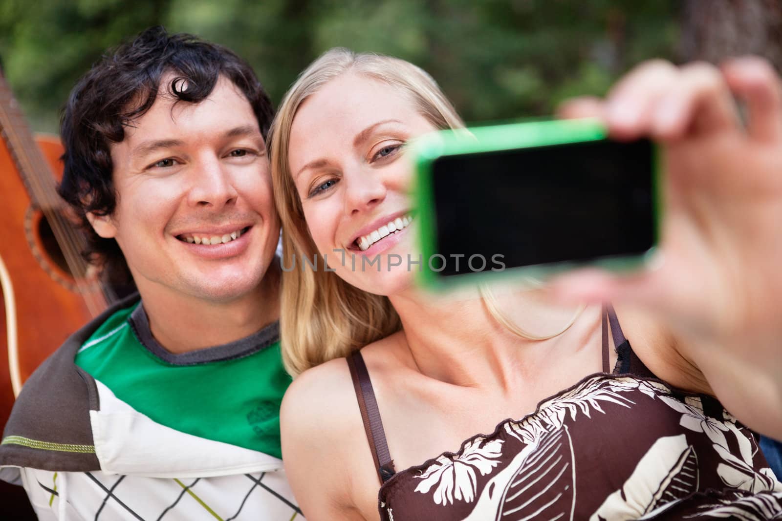 Young cheerful couple photographing themselves by leaf
