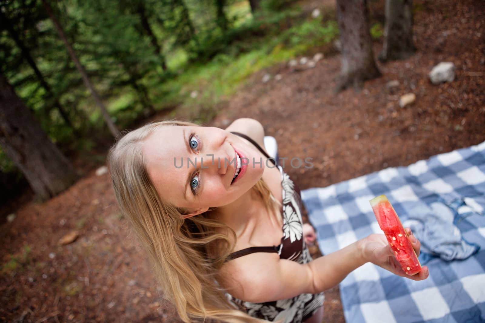 Top view of beautiful blond woman eating watermelon on picnic