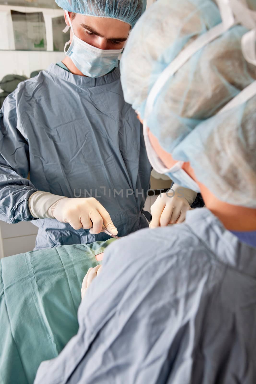 Surgeon with assistant performing operation