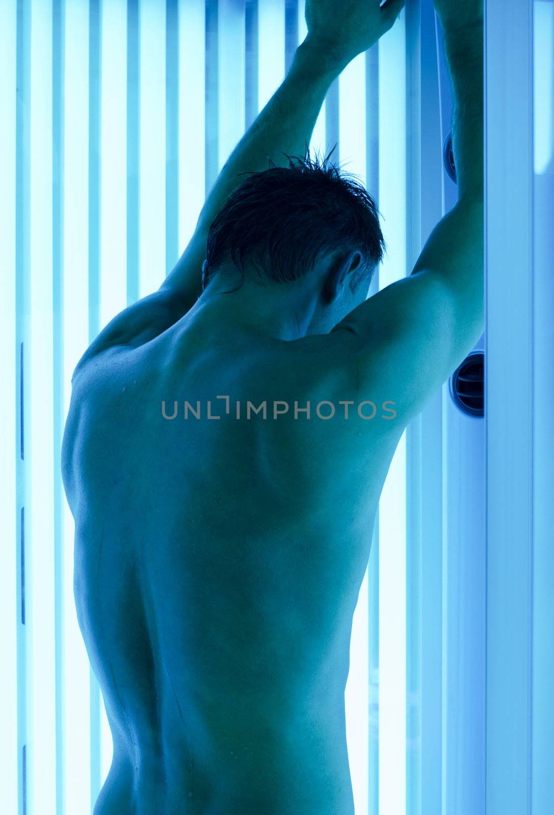 young man closeup at tanning solarium light on