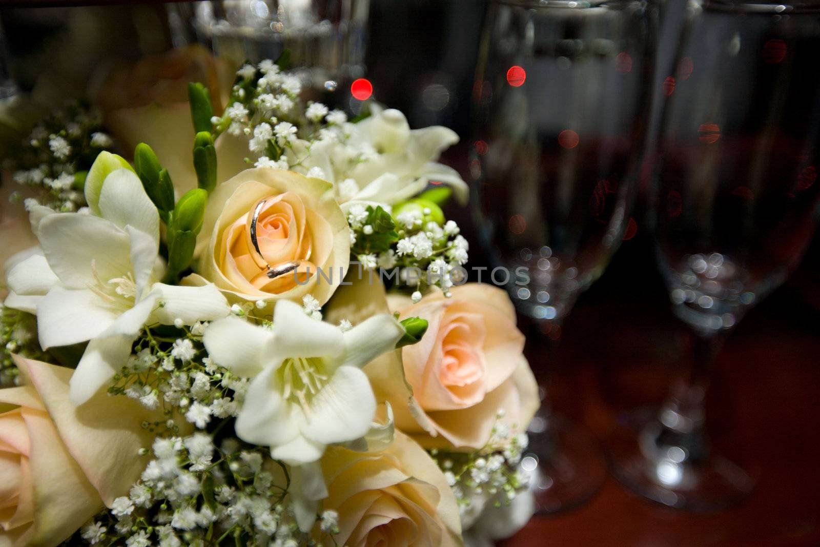 Two wedding rings on bouquet  near glasses