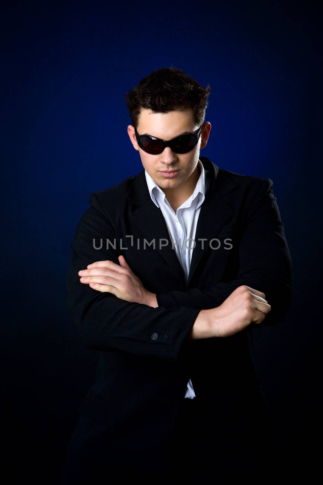 Young Man wearing suit and sunglasses over dark background