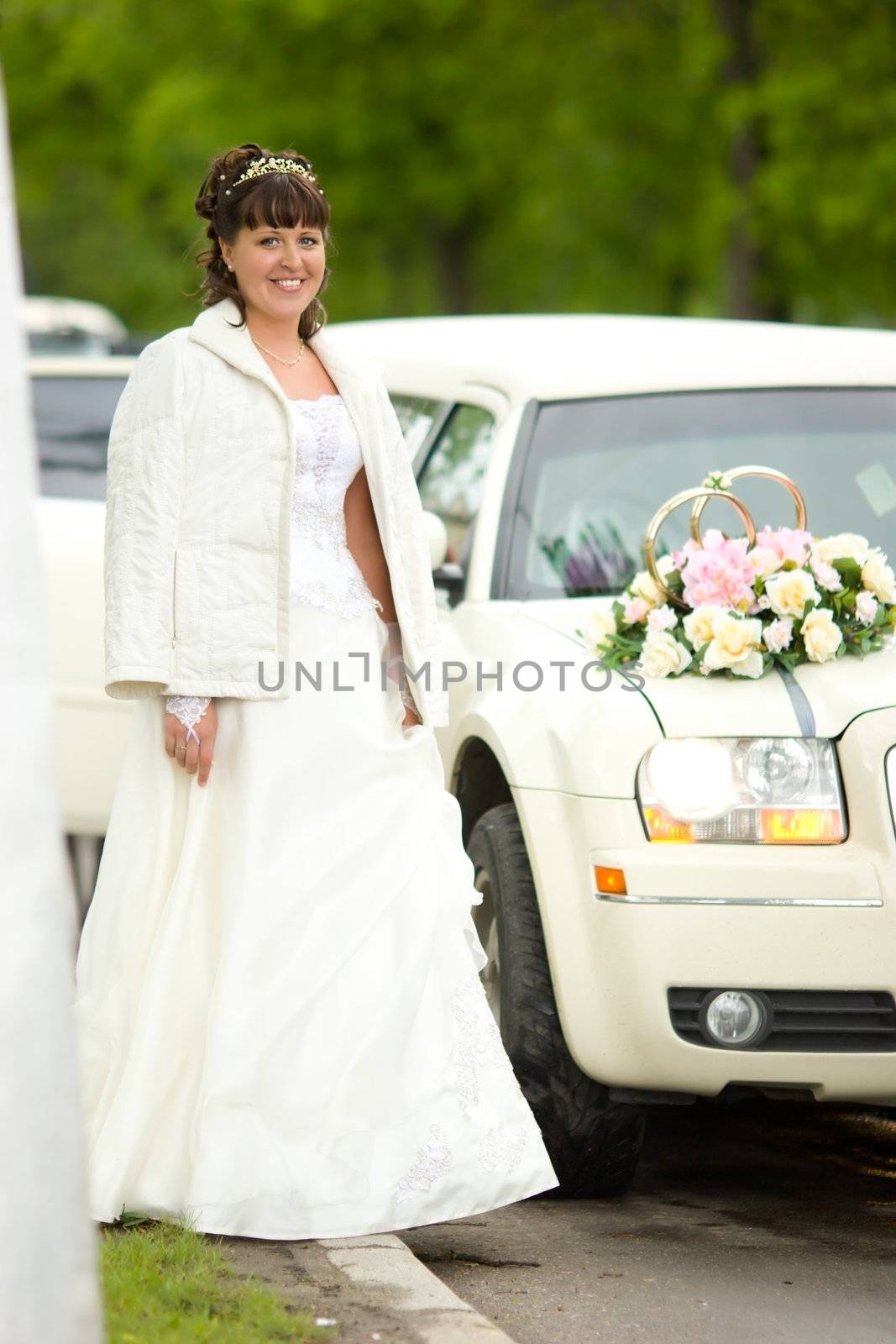 Bride standing near limo before wedding begins