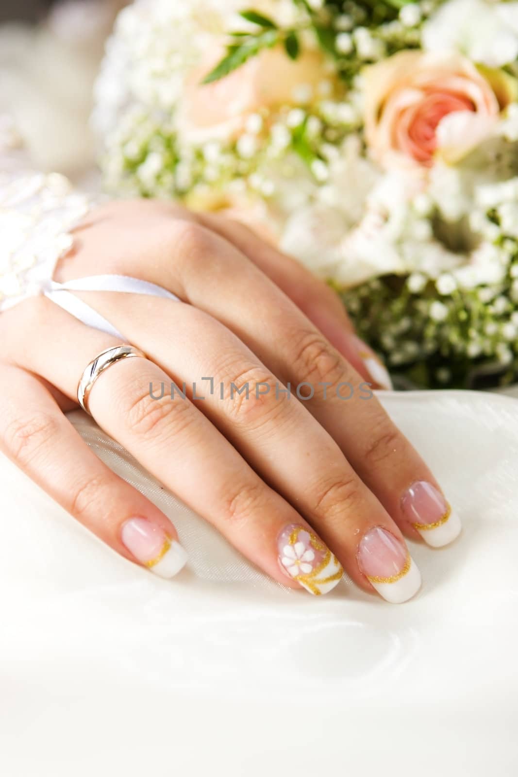 Bride's hand with golden ring and bouquet