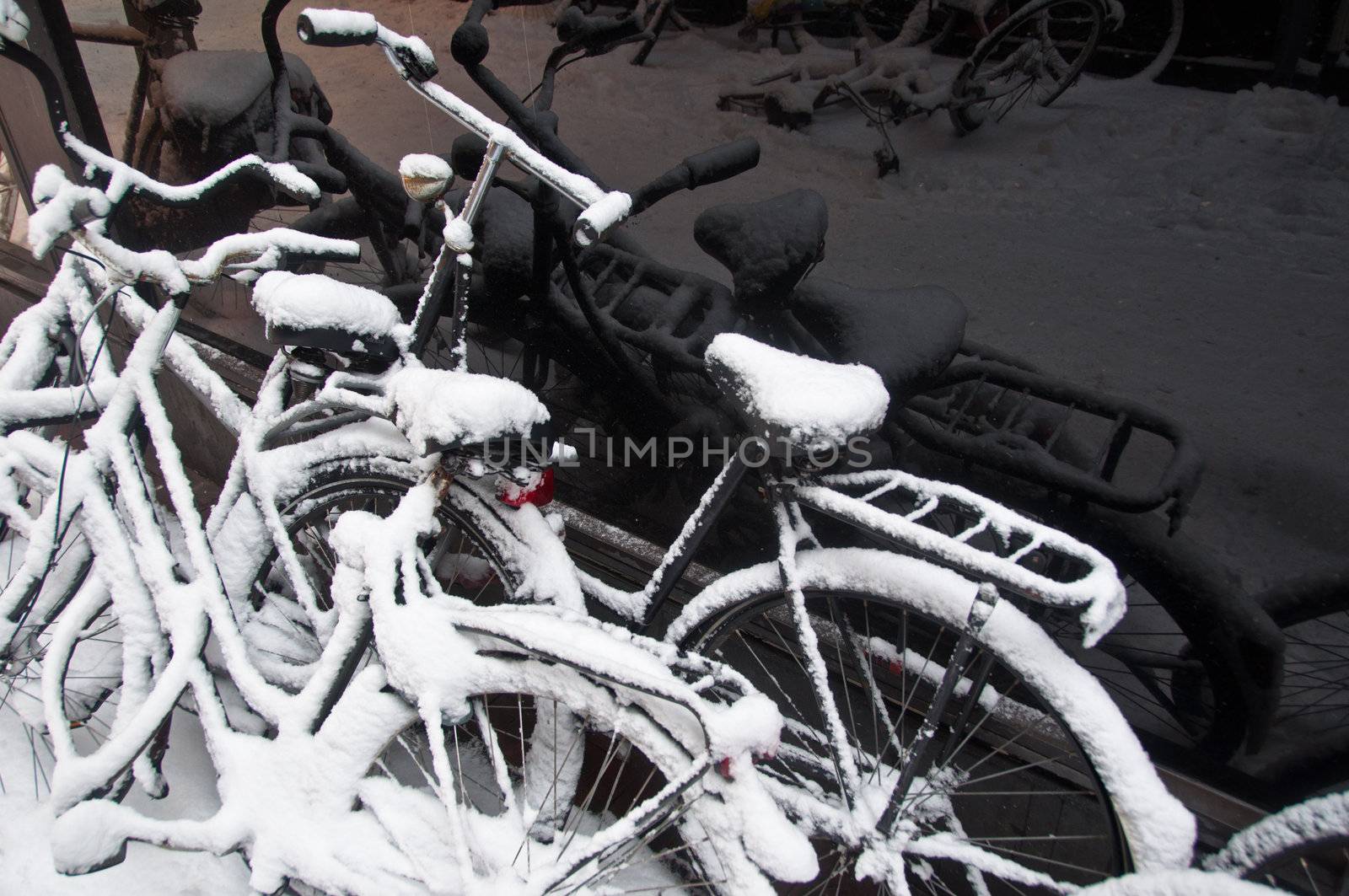snow-covered bikes after a blizzard with reflections in black shopping window