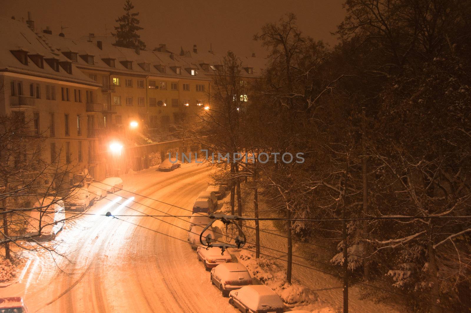 Main street covered with fresh snow and cars finding their way at night