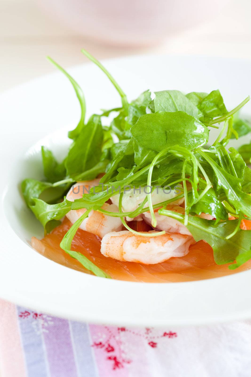 Fresh salad with smoked salmon and prawns topped with arugula