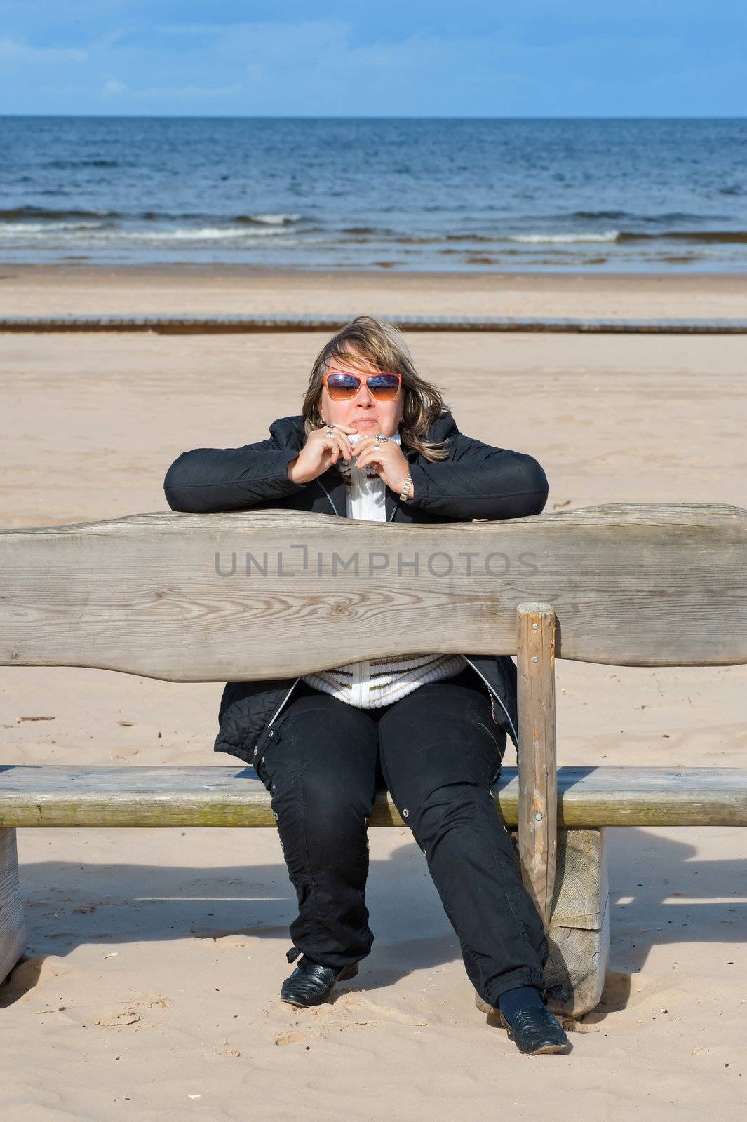 Mature chubby woman relaxing at the Baltic sea in autumn day.