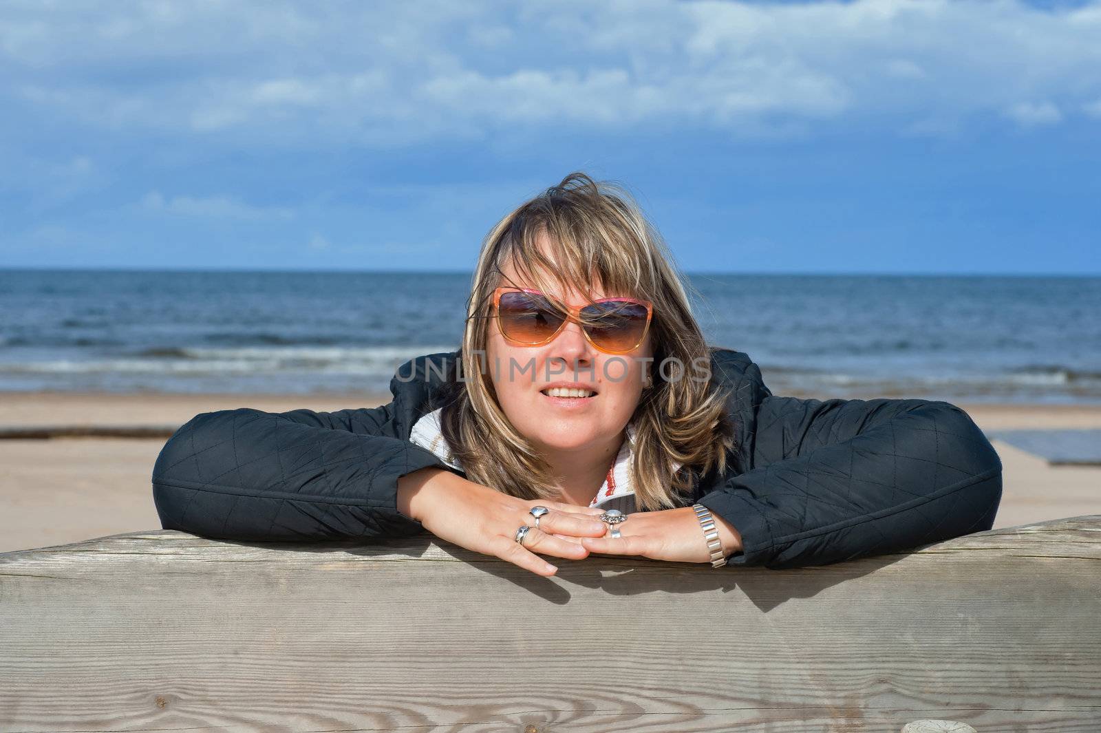 Portrait of mature woman in sunglasses relaxing at the Baltic sea in autumn day.
