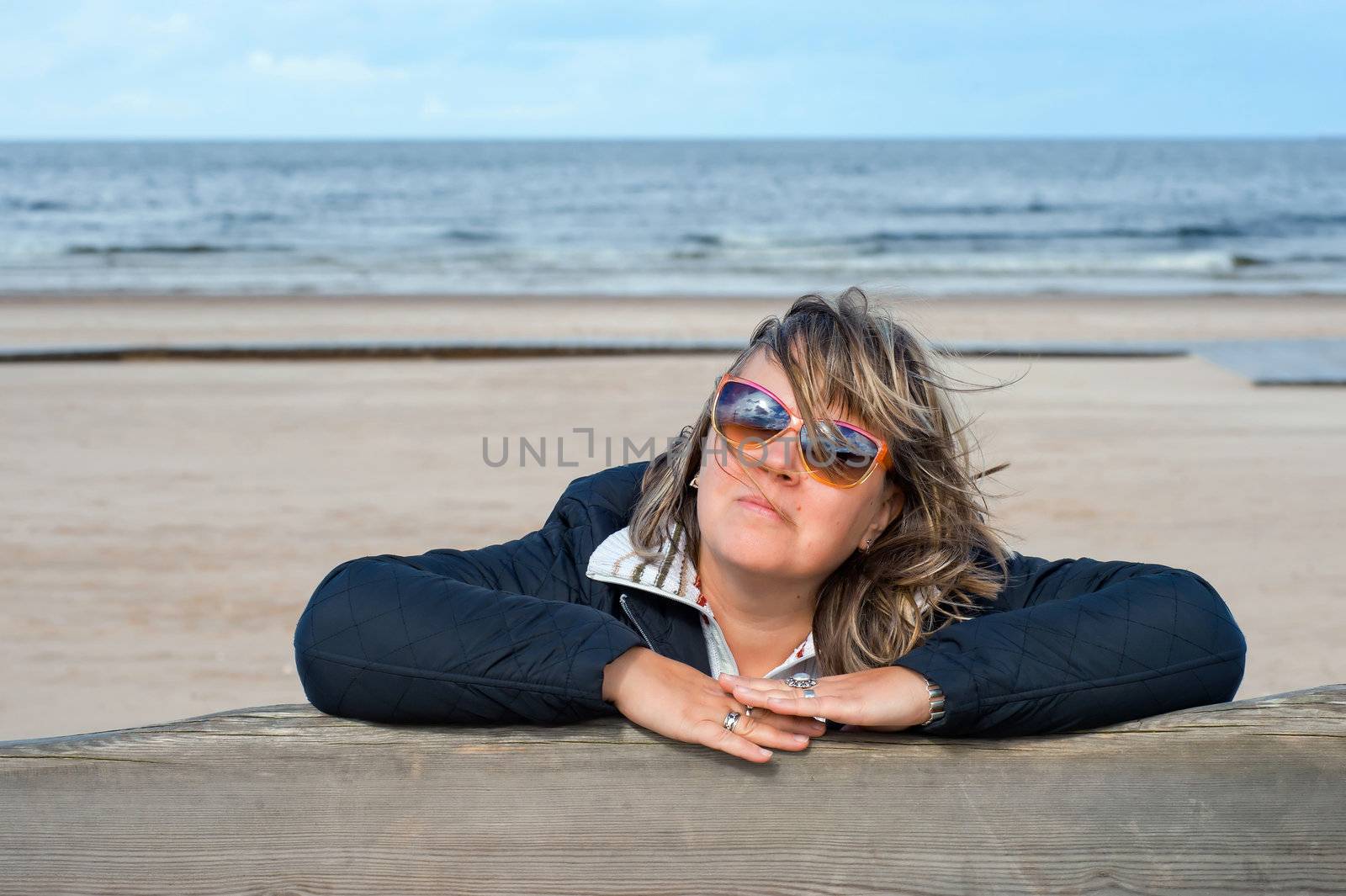 Portrait of mature woman in sunglasses relaxing at the Baltic sea in autumn day.