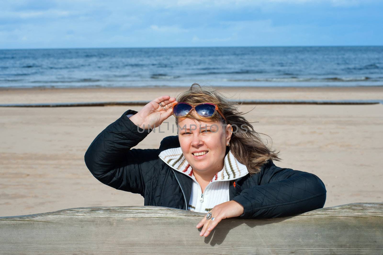 Portrait of mature woman in sunglasses relaxing at the Baltic sea in autumn day.