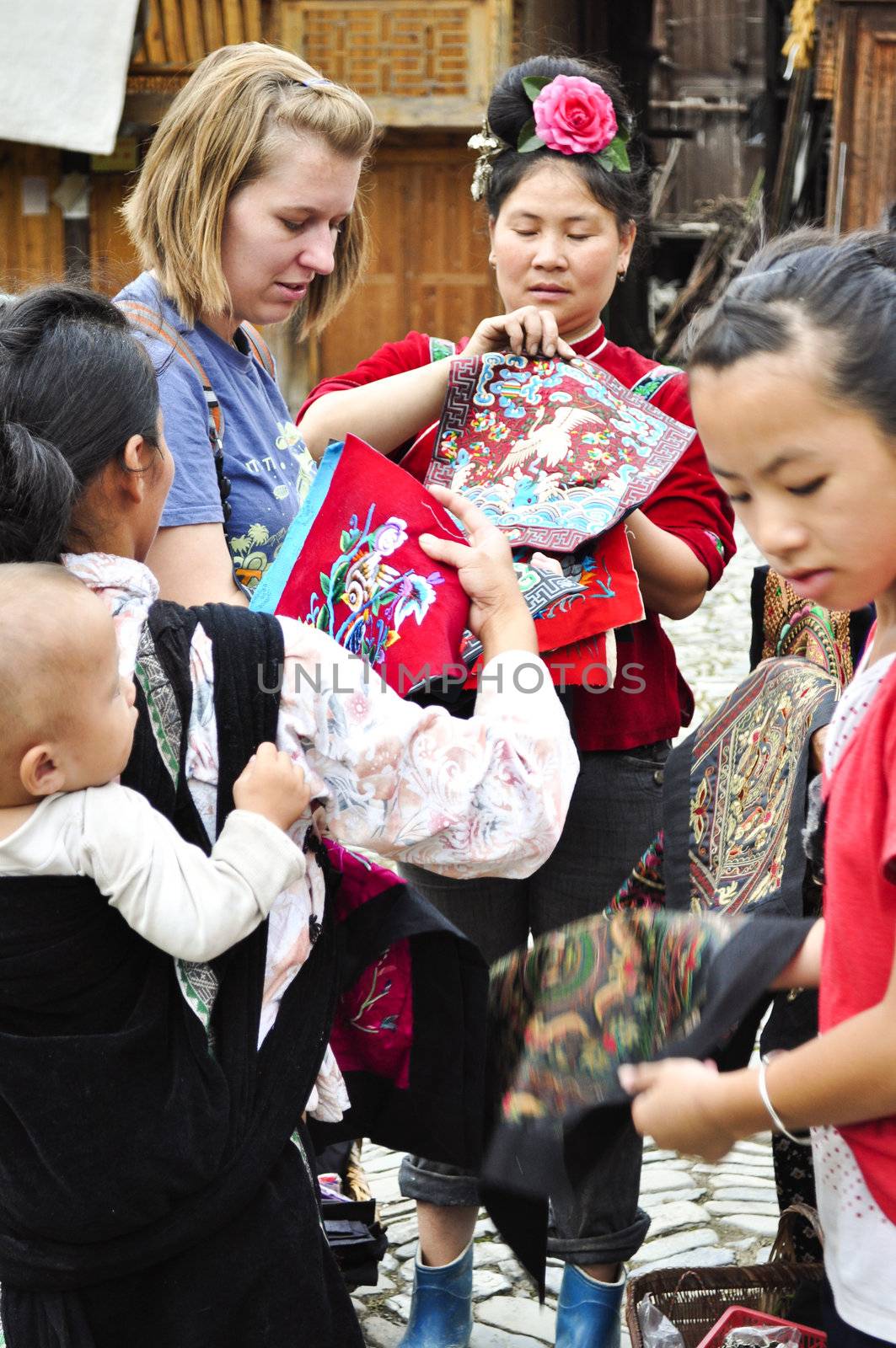 xijiang, China - July 02:  A young tourist is surrounded by a group of Chinese minority women trying to sell their goods on July 02, 2011.  A very popular tourist destination in China.