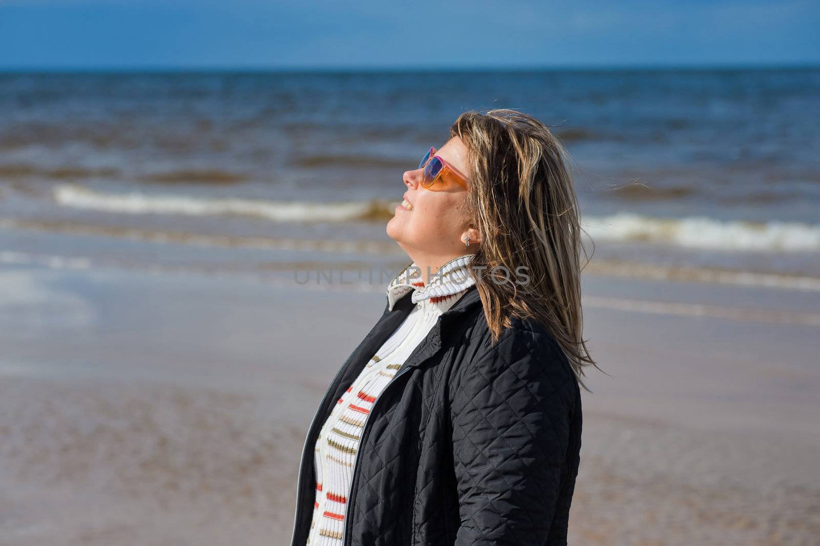 Portrait of mature woman in sunglasses relaxing at the Baltic sea in autumn day.