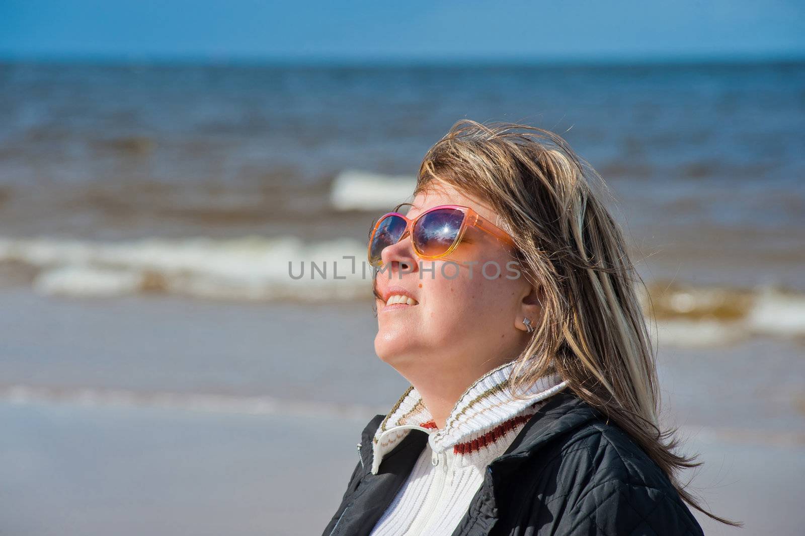 Portrait of mature woman in sunglasses relaxing at the Baltic sea in autumn day.