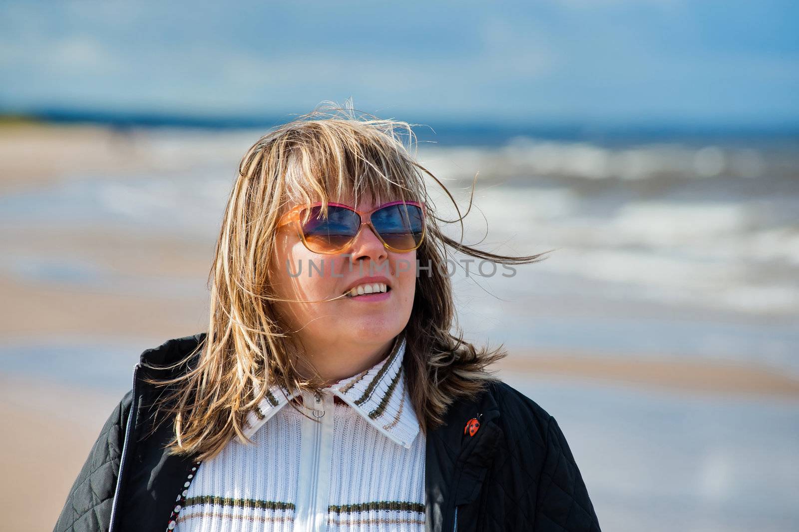 Portrait of mature woman in sunglasses relaxing at the Baltic sea in autumn day.