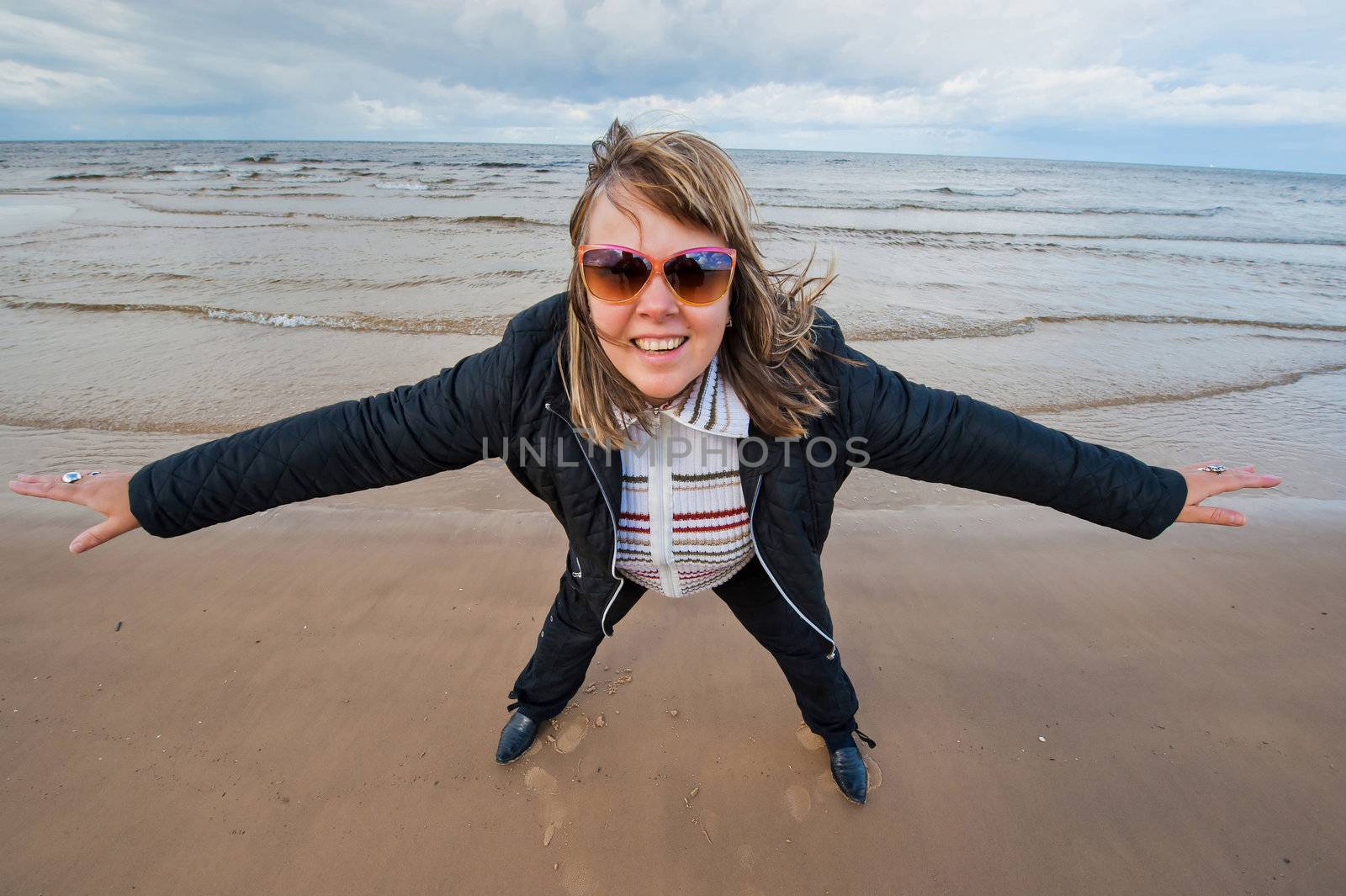 Mature funny attractive woman in sunglasses relaxing at the Baltic sea in autumn day.