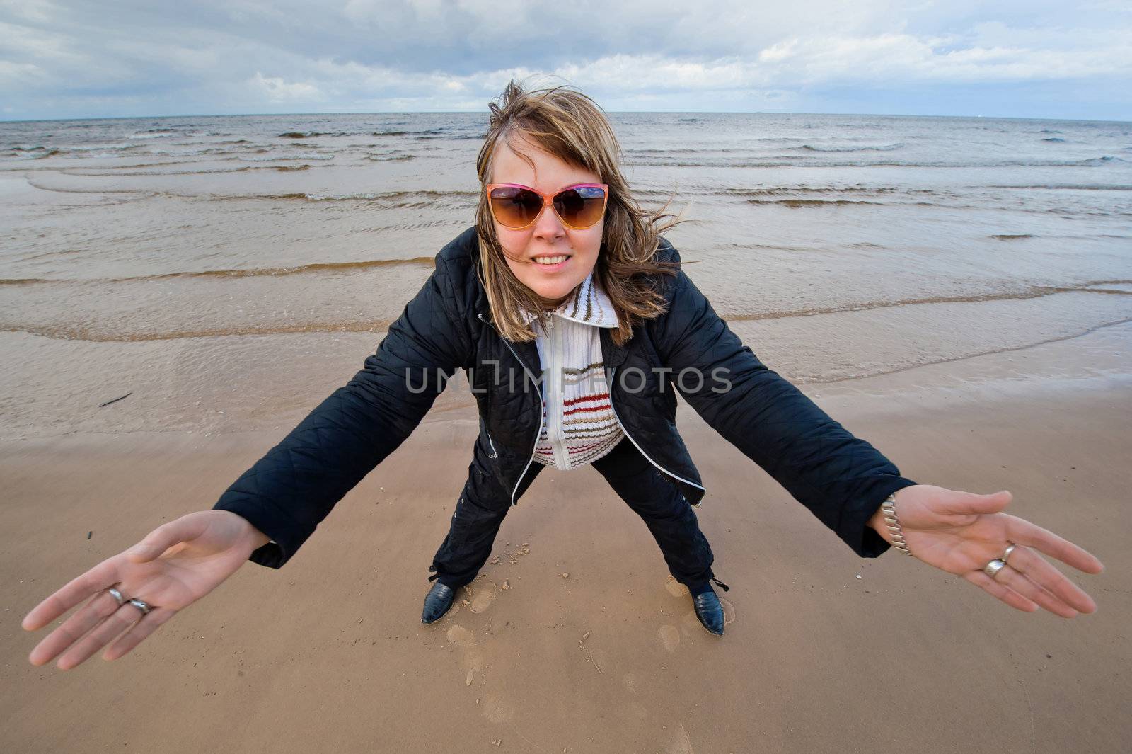 Mature funny attractive woman in sunglasses relaxing at the Baltic sea in autumn day.