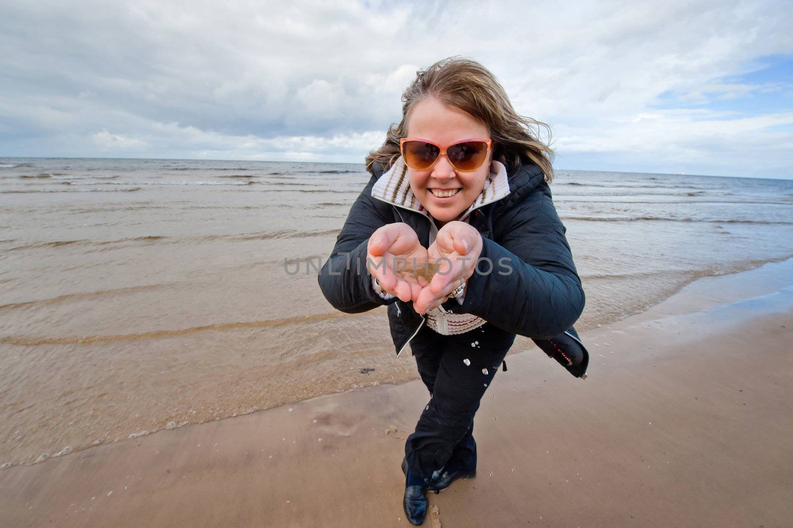 Mature funny attractive woman in sunglasses relaxing at the Baltic sea in autumn day.