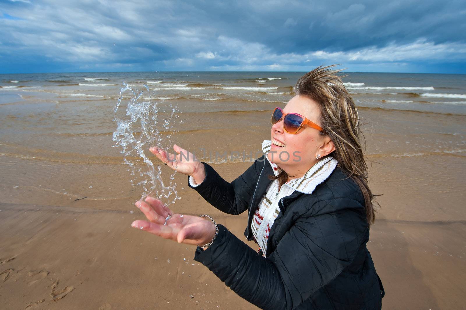 Mature attractive woman in sunglasses relaxing at the Baltic sea in autumn day.