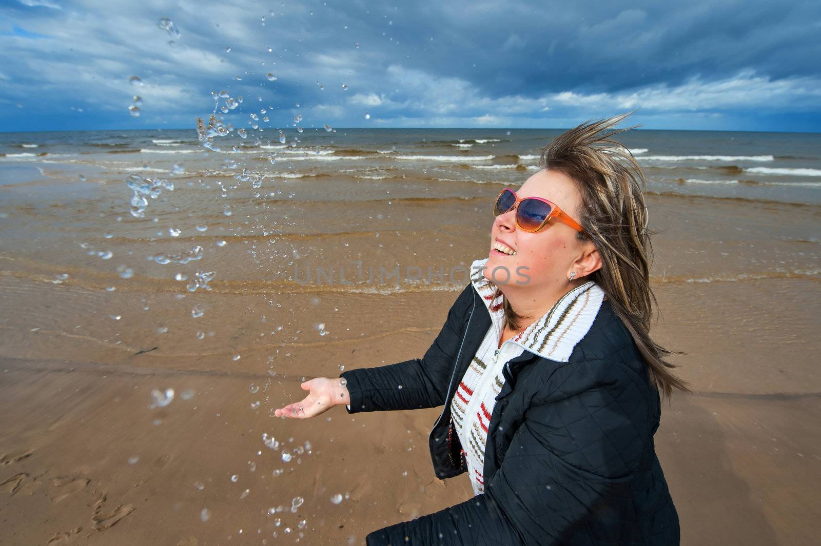 Mature funny attractive woman in sunglasses relaxing at the Baltic sea in autumn day.