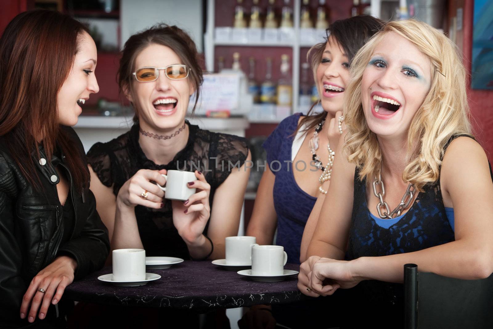 Pretty young blonde laughing with three friends in a cafe