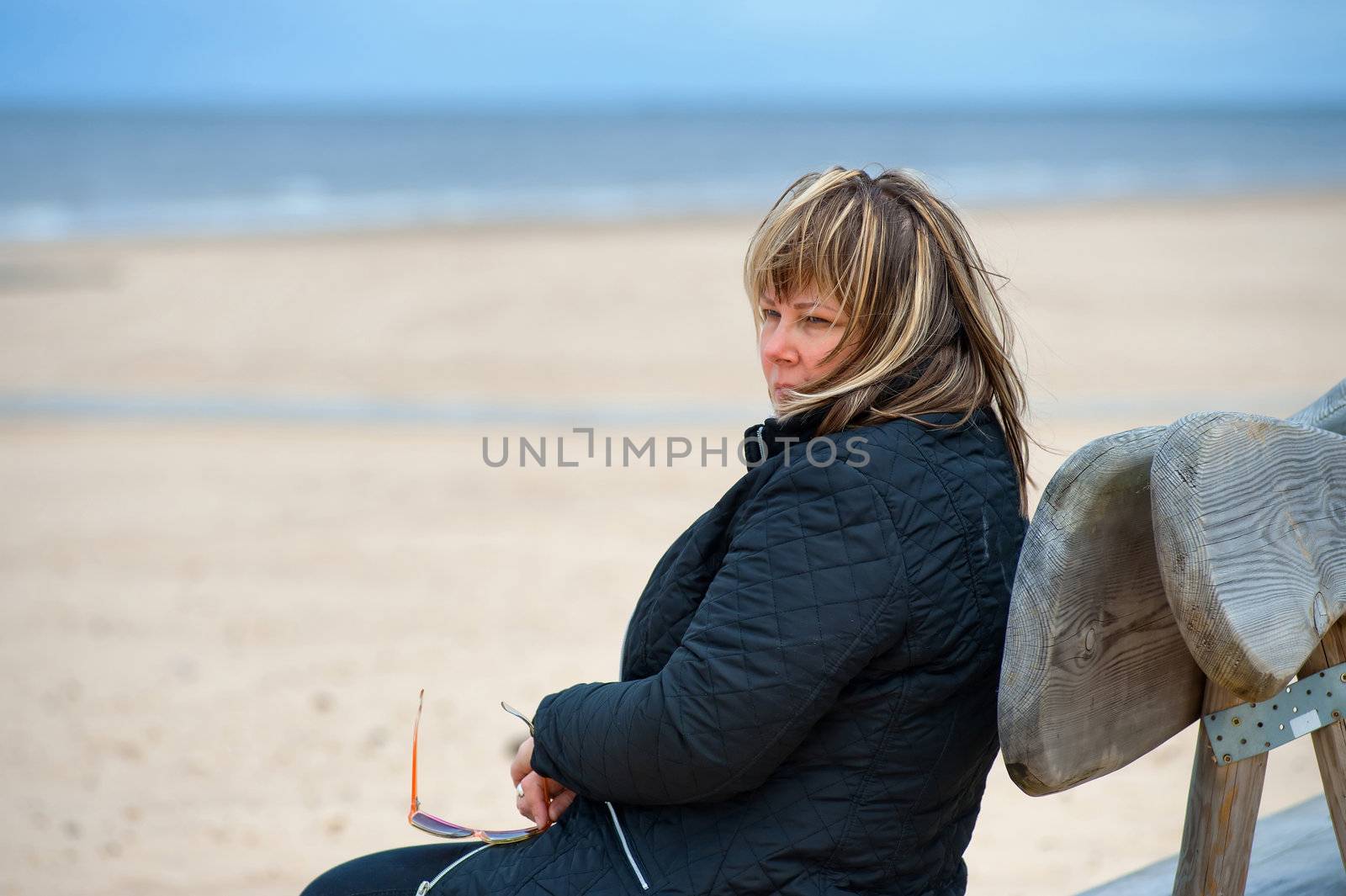 Mature woman relaxing at the Baltic sea in autumn day.